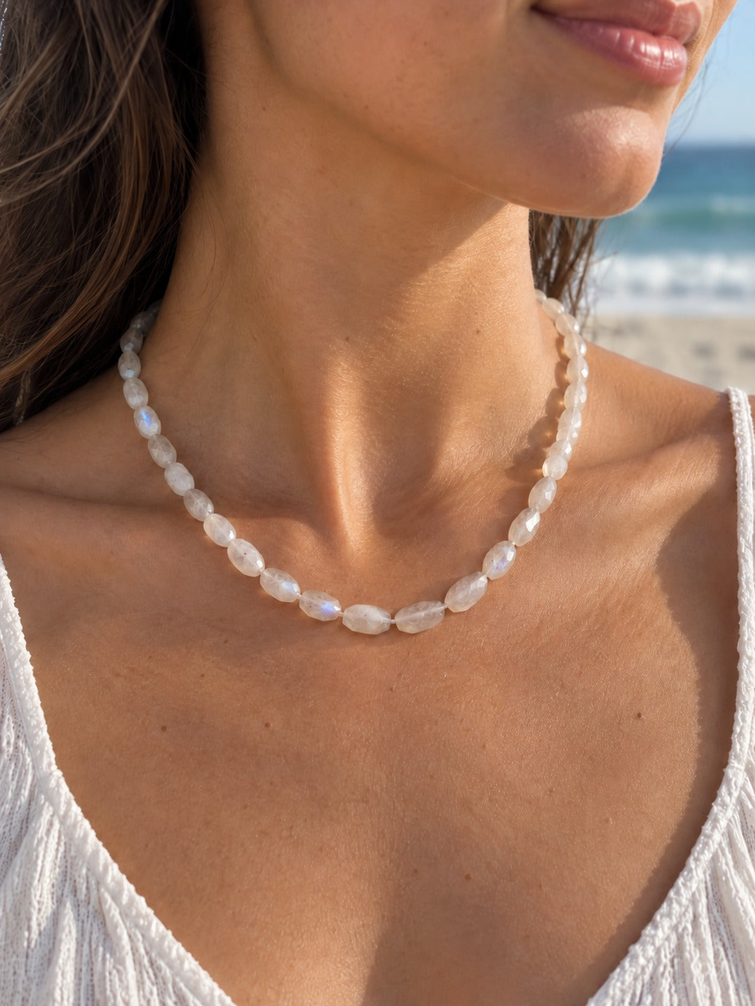 Rainbow moonstone faceted oval necklace on model at the beach