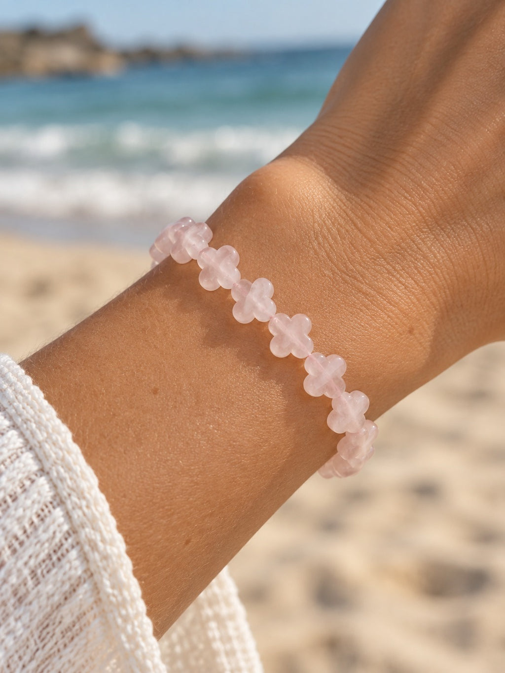 Rose quartz clover beaded bracelet on wrist at the beach